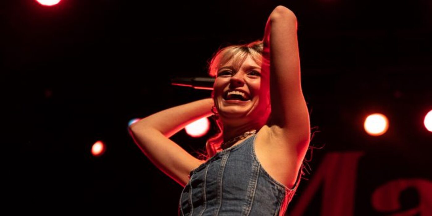 photo of Maisie Peters singing with a guitar.